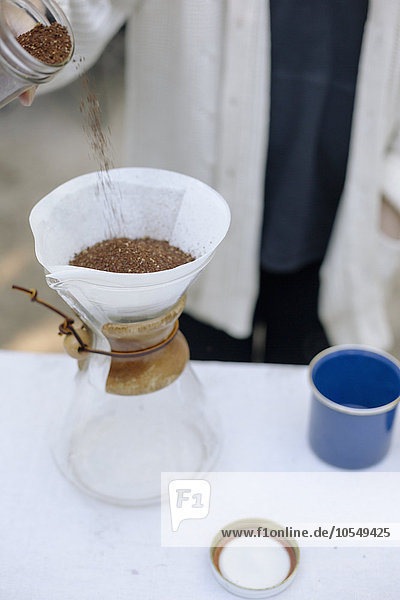 Hochwinkelansicht einer Glas-Kaffeemaschine  einer konischen Dose mit Filterpapier und Kaffeesatz.