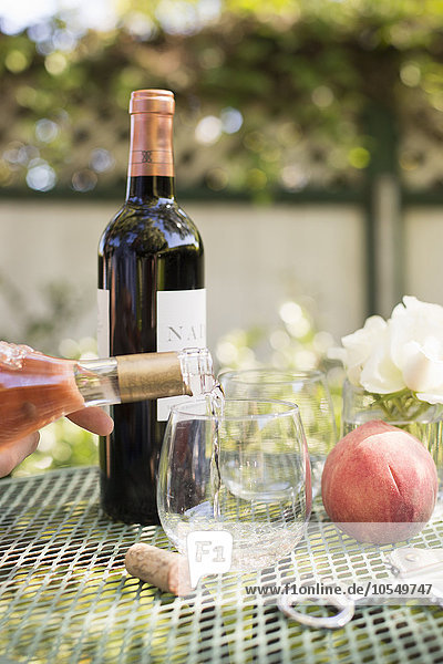 Rosenwein  der aus einer Weinflasche in ein Glas gegossen wird.