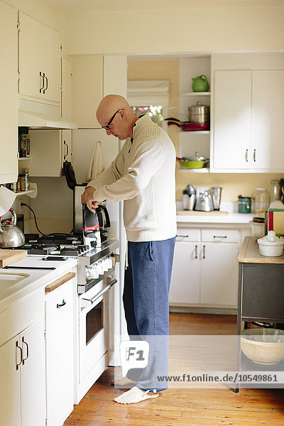 Man standing in a kitchen  making coffee.