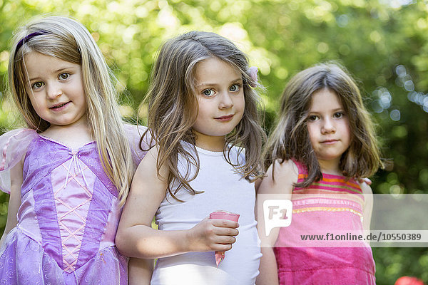 Drei lächelnde junge Mädchen bei einer Gartenparty.