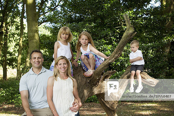 Family with three children by a tree in a forest  posing for a picture.