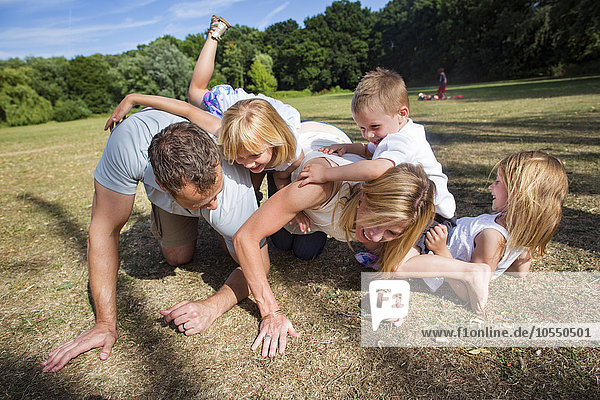 Familie mit drei Kindern  die in einem Park spielen.