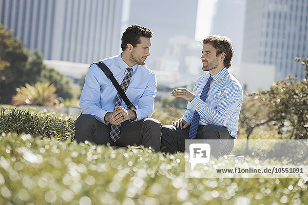 Zwei Männer in Hemd und Krawatte in einem Park in der Stadt.