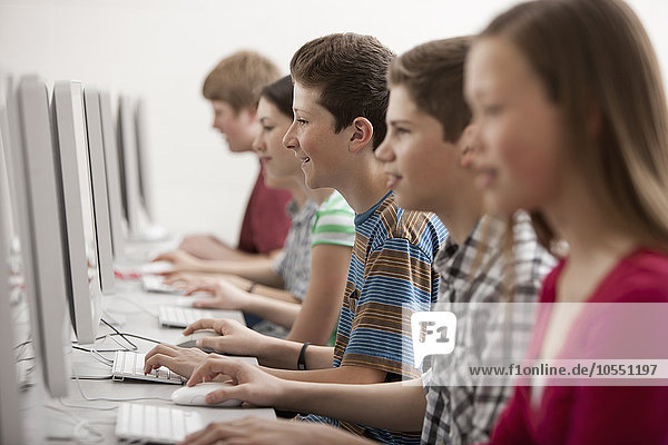 Eine Gruppe von Jugendlichen  Jungen und Mädchen  Studenten in einer Computerklasse  die an Bildschirmen arbeiten.
