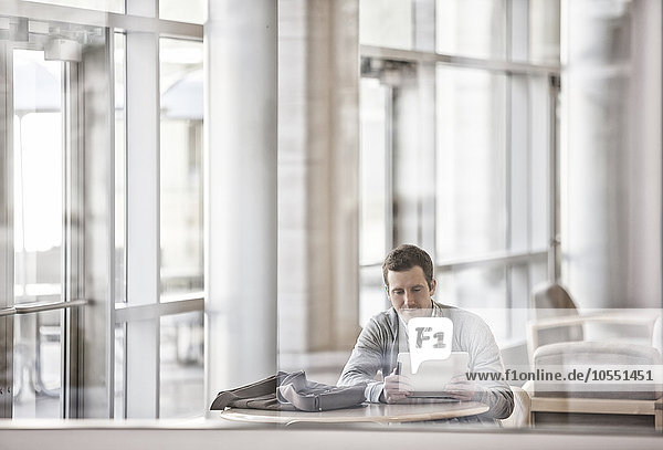 Ein Mann sitzt in einem Großraumbüro am Fenster und schaut auf einen Laptop.