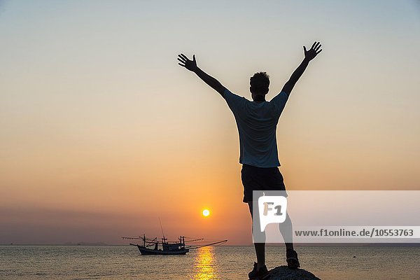 Silhouette eines jungen Mannes  Boot im Meer bei Sonnenuntergang  Insel Koh Samui  Golf von Thailand  Thailand  Asien
