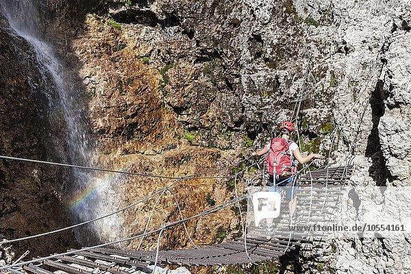 Bergsteiger auf Hängebrücke mit Wasserfall  Klettersteig Vallonsteig  Piz Boé  Sella Gruppe  Dolomiten  Corvara  Südtirol  Trentino-Südtirol  Alpen  Italien  Europa