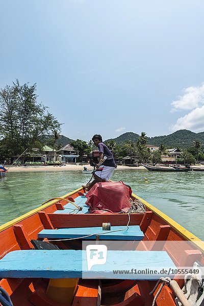 Local man steering longtail boat from rear  turquoise sea  island of Koh Tao  Gulf of Thailand  Thailand  Asia