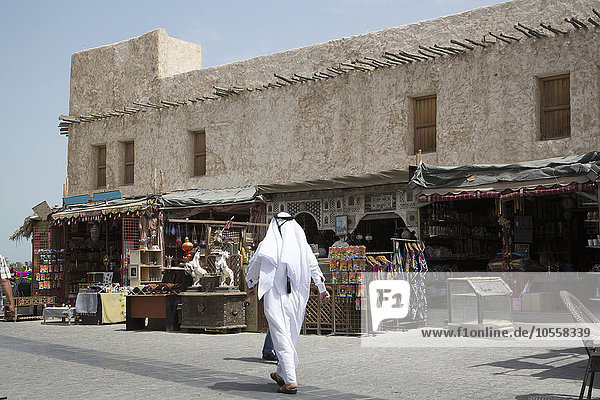 Man walking outside market on Doha sidewalk  Doha  Qatar