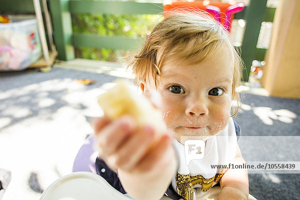 Caucasian baby girl eating on patio