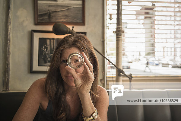Kaukasische Frau schaut durch ein leeres Glas in einem Cafe
