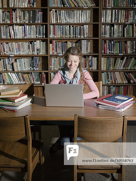 Studentin benutzt Laptop in der Bibliothek