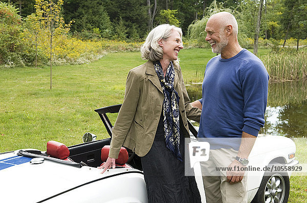 Older couple standing by convertible