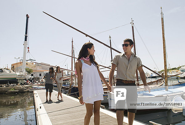 Couple walking on wooden dock in urban harbor