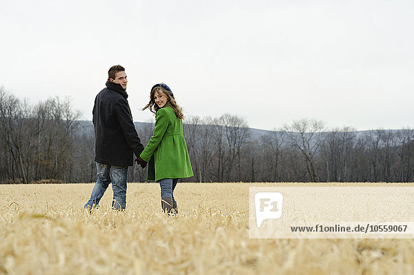 Caucasian couple walking in rural field