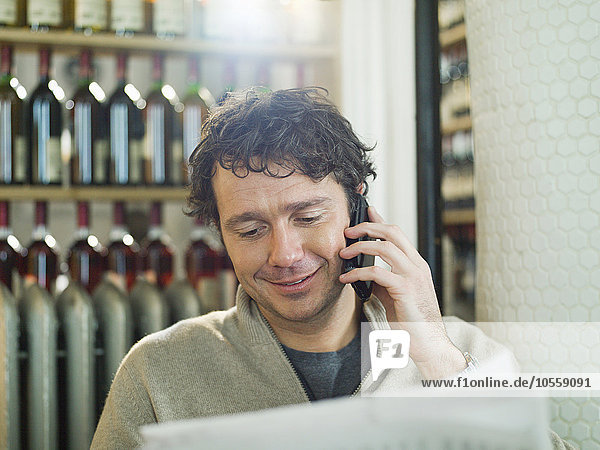 Kaukasischer Mann  der in einem Restaurant mit seinem Handy telefoniert