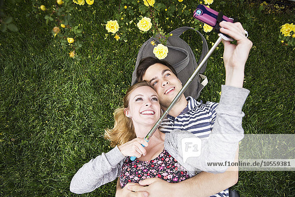 Kaukasisches Paar macht Selfie mit Handy im Gras