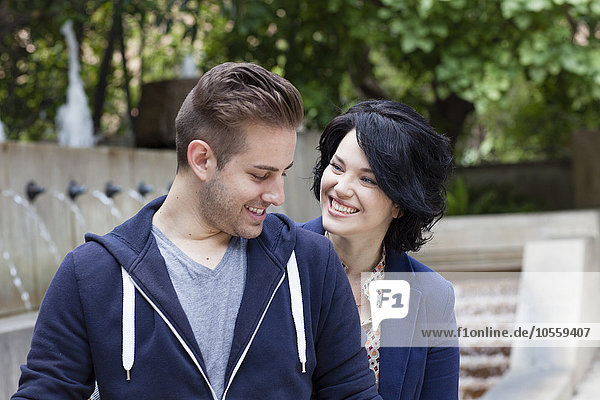 Caucasian couple smiling by urban fountain