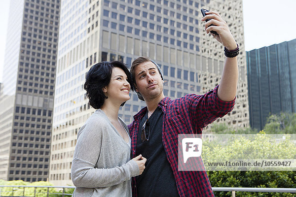 Kaukasisches Paar macht Selfie mit Handy in der Stadt