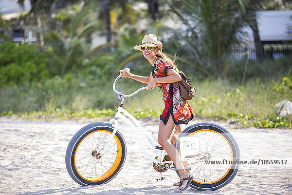 Hispanische Frau fährt Fahrrad am Strand