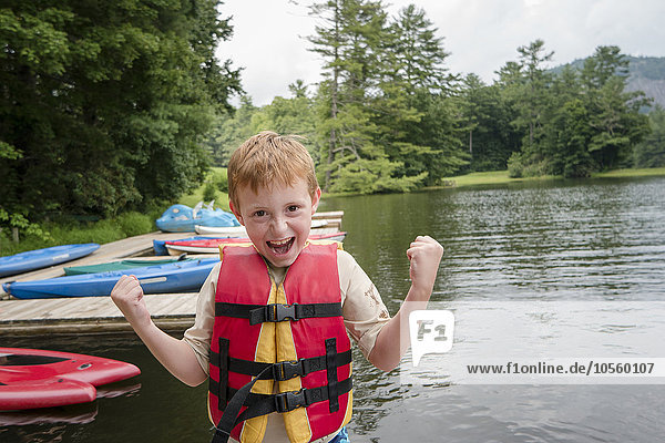 Caucasian boy wearing lifejacket by lake