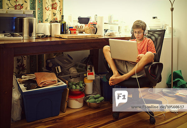 Gemischtrassiger Junge benutzt Laptop im Wohnzimmer