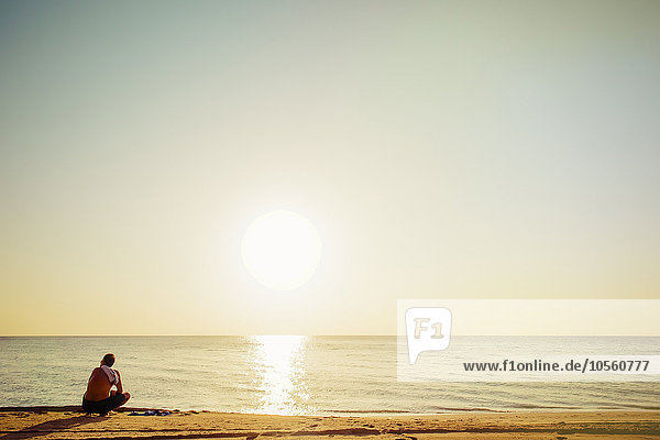 Gemischtrassiger Mann sitzt am Strand