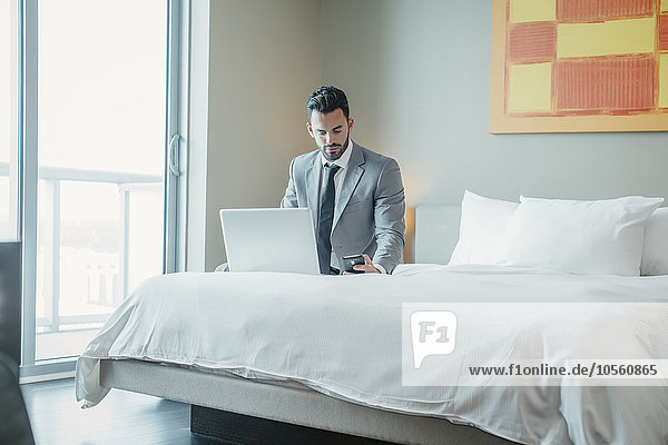 Businessman using laptop on hotel bed