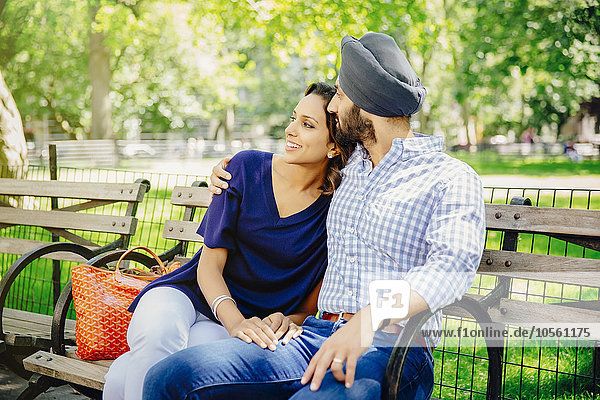 Indian couple hugging on bench in urban park