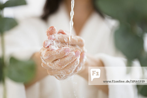 Gemischtrassige Frau wäscht ihre Hände im Wasser