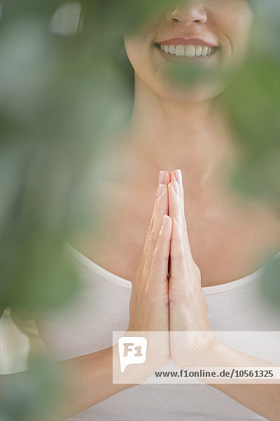 Gemischtrassige Frau meditiert mit gefalteten Händen