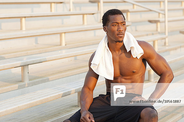 Black athlete sitting on bleachers