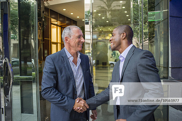 Businessmen shaking hands at office building