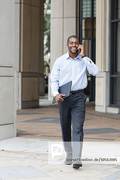 Black businessman talking on cell phone on city sidewalk