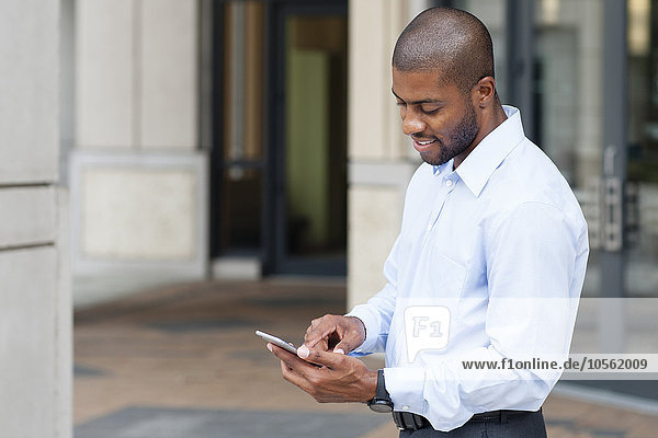 Black businessman using cell phone outside office