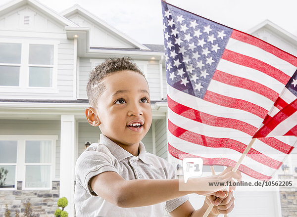 Gemischtrassiger Junge schwenkt amerikanische Flagge