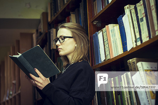 Kaukasische Frau liest ein Buch in der Bibliothek