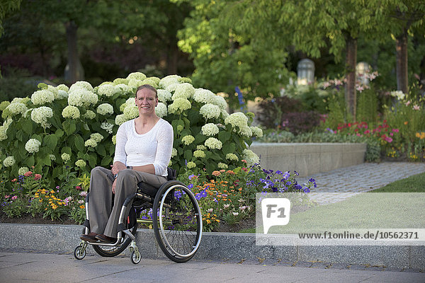 Behinderte Frau im Rollstuhl auf einer Straße in der Stadt