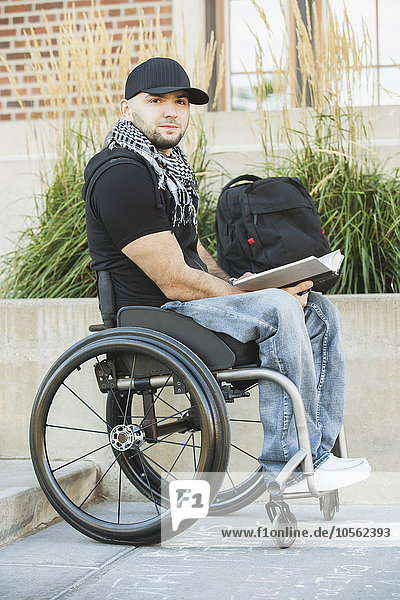 Behinderter Student im Rollstuhl liest Buch