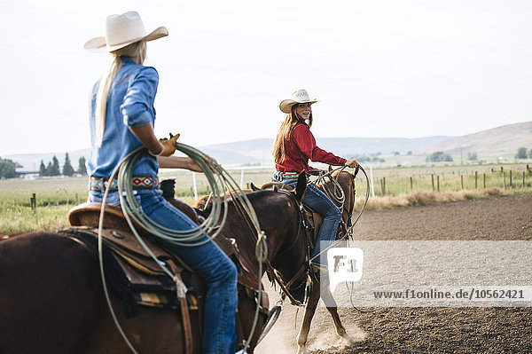 Kaukasische Cowgirls reiten auf einer Ranch