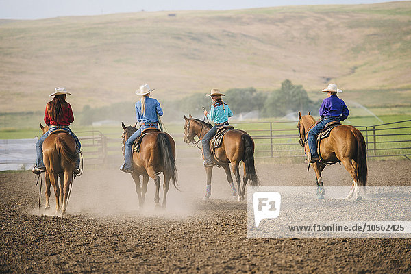 Cowgirls and cowboy riding horses on ranch
