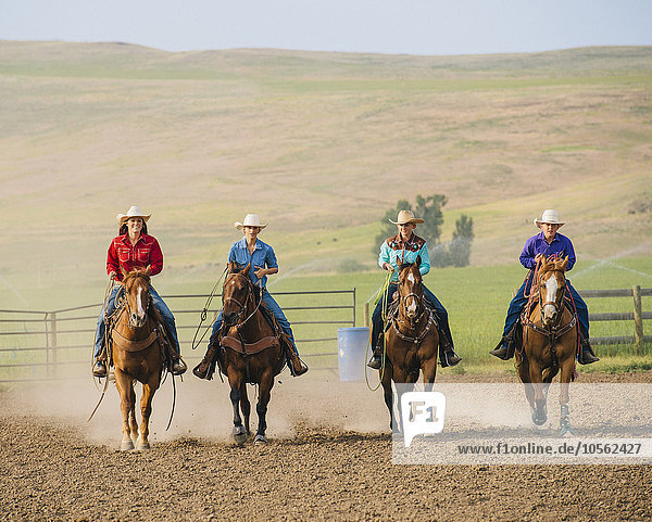 Cowgirls and cowboy riding horses on ranch