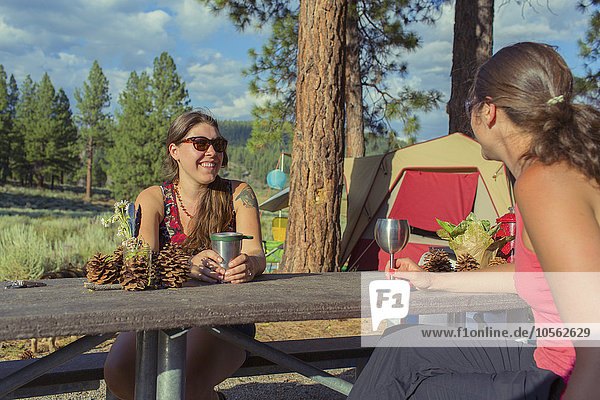 Kaukasische Frauen trinken Wein auf dem Campingplatz