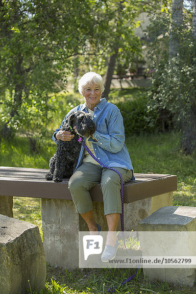 Ältere kaukasische Frau umarmt Hund im Park