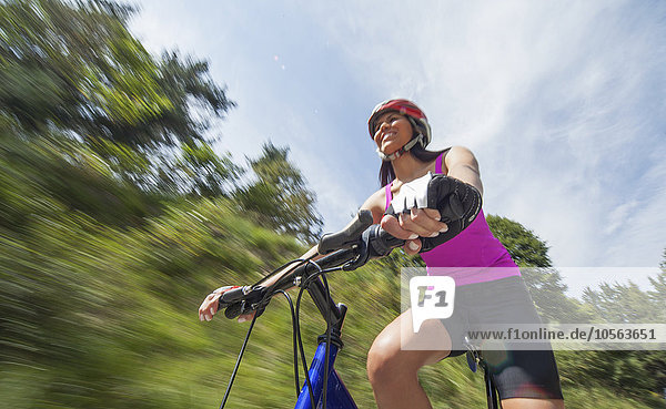 Hispanic woman riding bicycle outdoors
