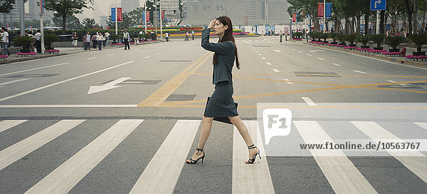 Chinesische Geschäftsfrau auf dem Fußgängerüberweg