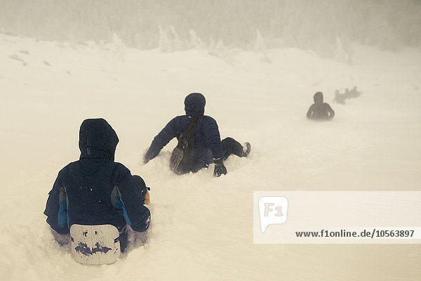 Kaukasische Wanderer beim Schlittenfahren auf einem verschneiten Hügel
