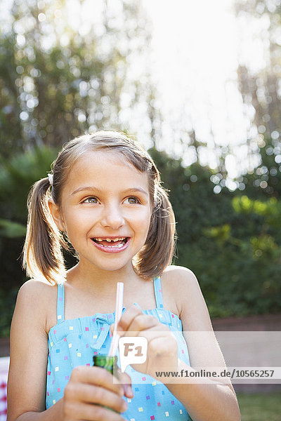 Smiling girl eating candy cigarette in backyard