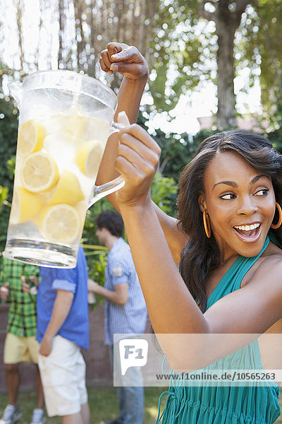 Woman holding pitcher of lemonade at backyard barbecue