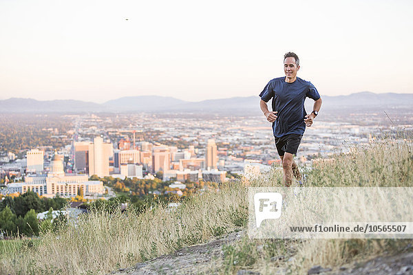 Mixed race man running on hilltop over Salt Lake City  Utah  United States